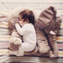 Neonato dorme con il suo piccolo pupazzetto elefante che lo protegge