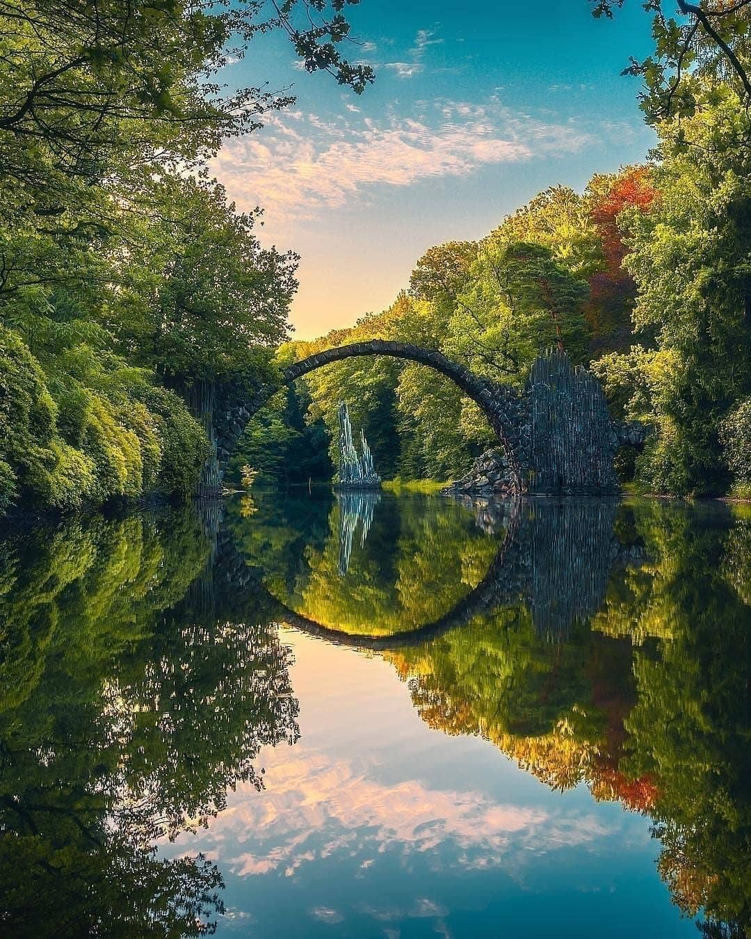 il ponte arcuato riflesso nello spechio d’acqua che passa sotto