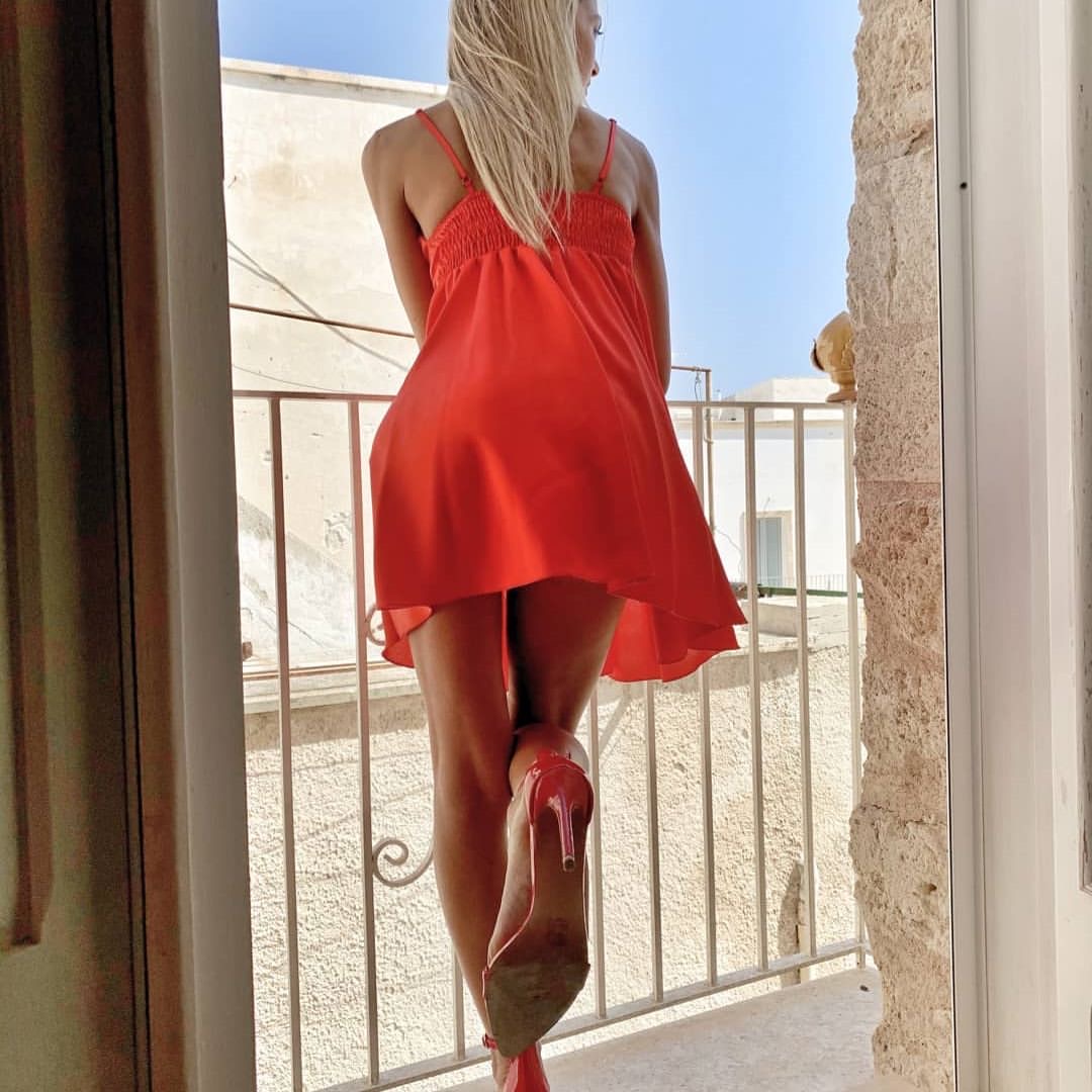 lei affacciata al balcone nel suo vestito disegnato dal vento