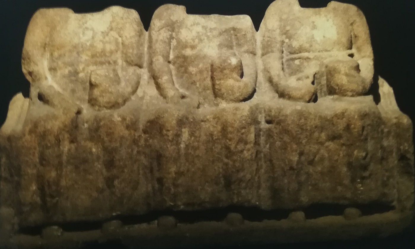 Scultura romana delle Matres sedute su una panca con indosso tuniche e che tengono in mano coppe e forse della frutta